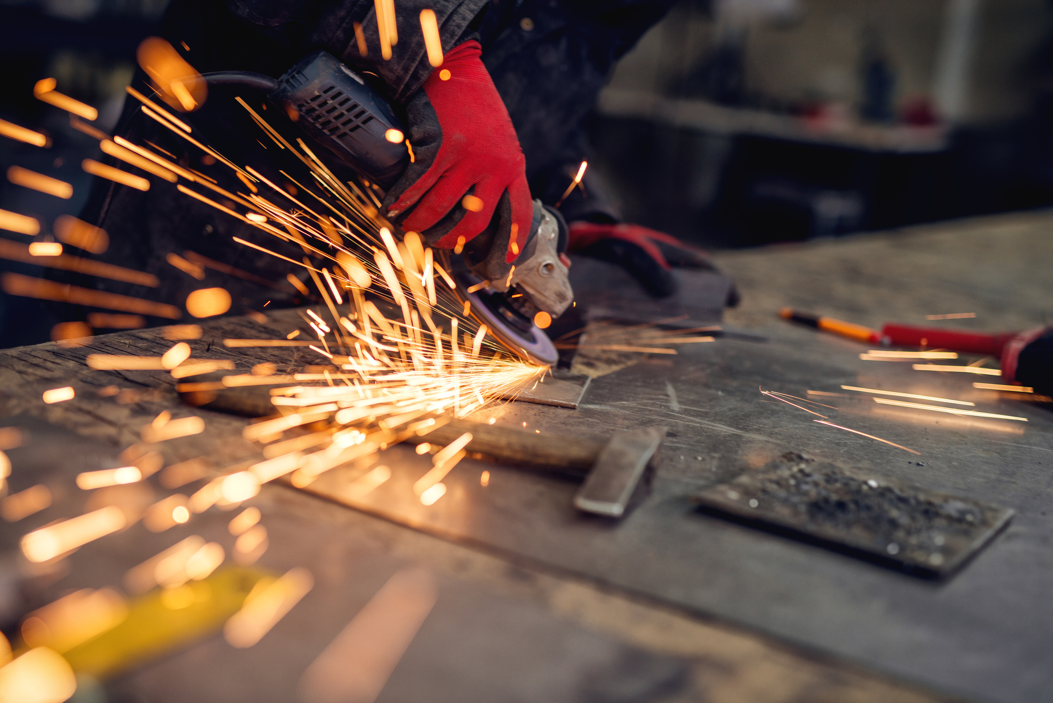 Craftsman sawing metal, sparkles around workshop.